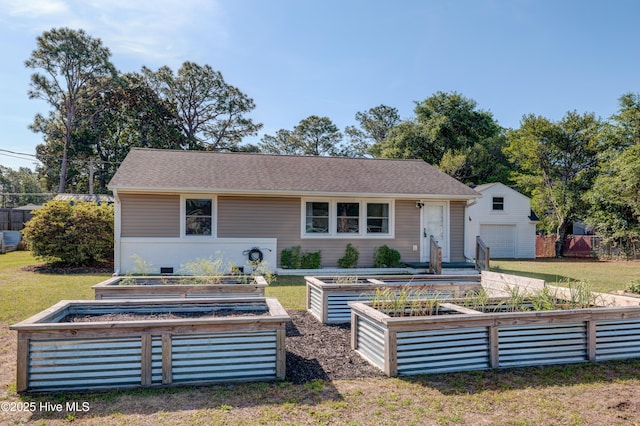 view of front of home with a front lawn, a vegetable garden, an outbuilding, and a shingled roof