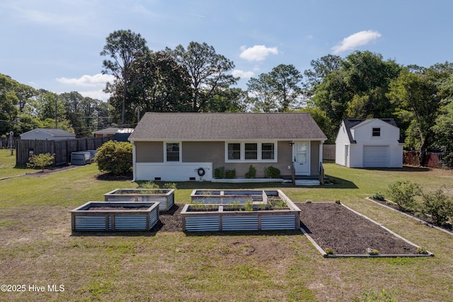back of house with a lawn, an outbuilding, a garden, and fence