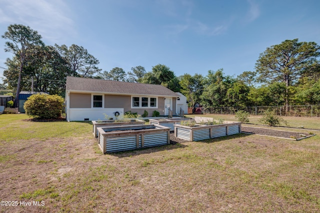 rear view of house with a yard, a vegetable garden, and fence