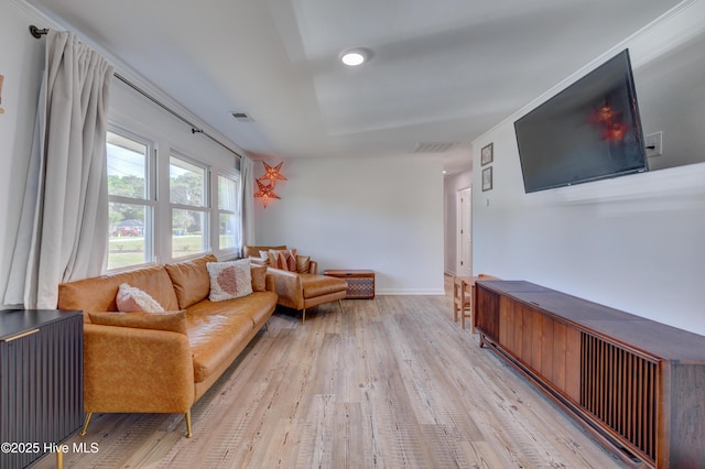 living room featuring light wood finished floors, visible vents, and baseboards