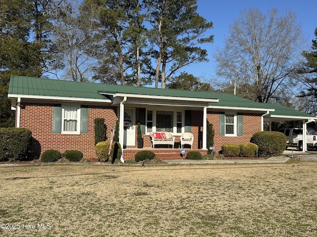 view of front facade featuring metal roof, a porch, an attached carport, brick siding, and a front yard