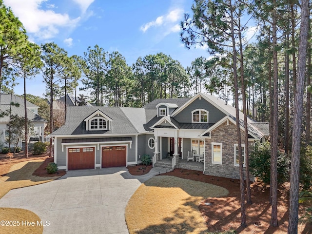 craftsman-style house with roof with shingles, concrete driveway, covered porch, a garage, and stone siding