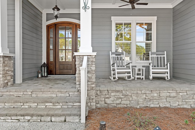 view of exterior entry featuring stone siding, a porch, and a ceiling fan