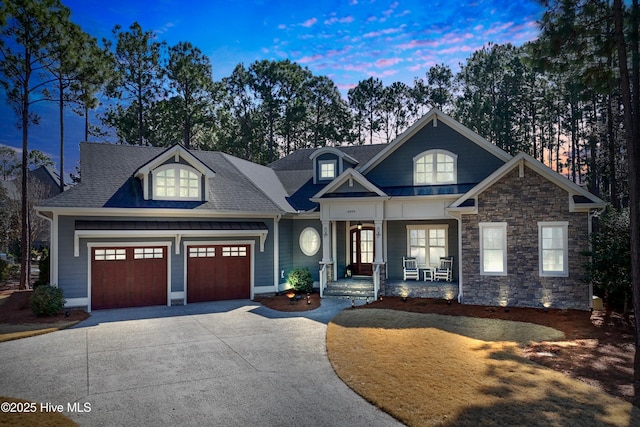 craftsman inspired home featuring driveway, covered porch, an attached garage, and roof with shingles