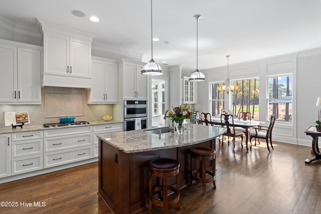 kitchen with stainless steel appliances, a sink, white cabinets, decorative backsplash, and crown molding