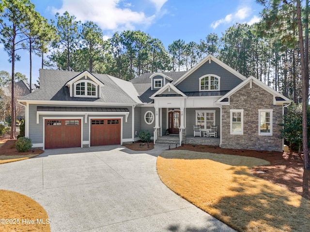 craftsman-style home featuring driveway, a shingled roof, metal roof, a standing seam roof, and a porch