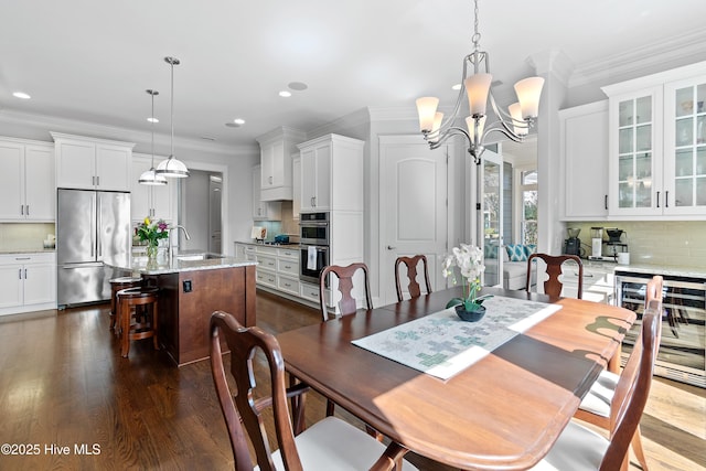 dining area featuring dark wood finished floors, wine cooler, ornamental molding, a chandelier, and recessed lighting