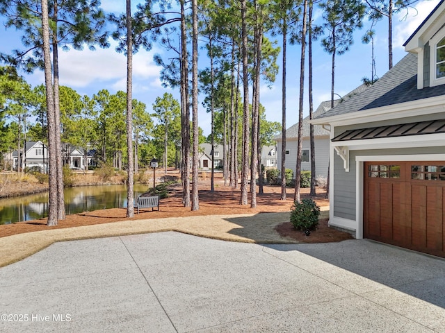 exterior space with driveway, a water view, and a garage