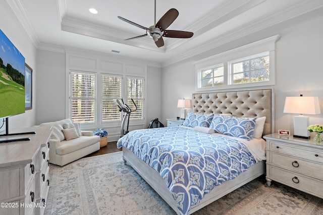 bedroom with a raised ceiling, visible vents, ornamental molding, a ceiling fan, and wood finished floors