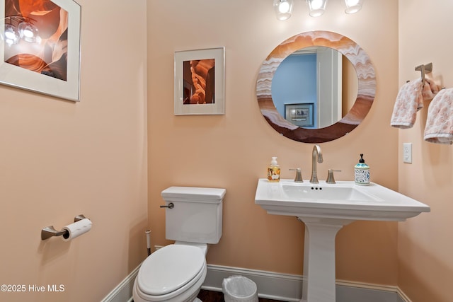 bathroom featuring a sink, toilet, and baseboards