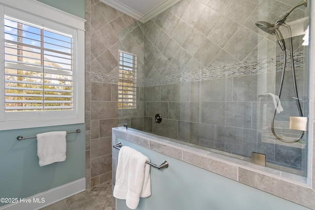 bathroom featuring tile patterned floors, crown molding, baseboards, and a walk in shower