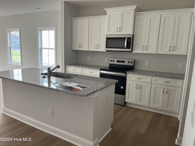 kitchen with a kitchen island with sink, dark wood-style flooring, a sink, white cabinets, and appliances with stainless steel finishes