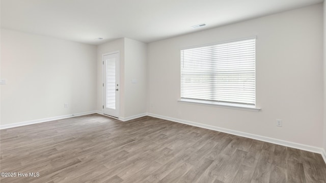 empty room with visible vents, baseboards, and wood finished floors