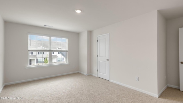 spare room featuring baseboards and light colored carpet