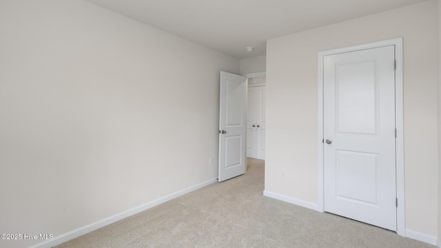 unfurnished bedroom featuring light carpet and baseboards