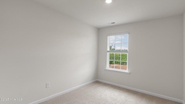 spare room with carpet, visible vents, and baseboards