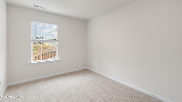 empty room featuring carpet flooring, visible vents, and baseboards