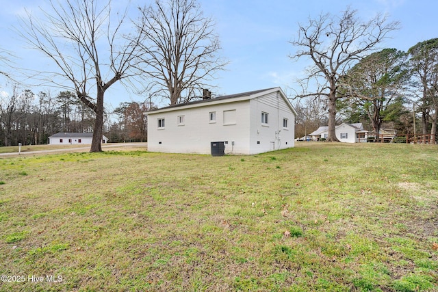 back of house featuring a chimney, central AC unit, and a lawn