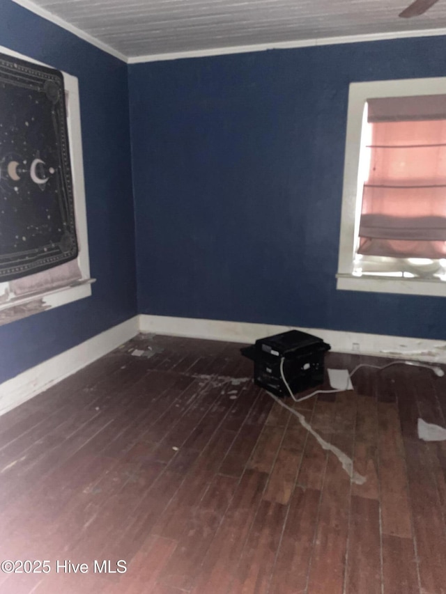 spare room featuring baseboards, wood finished floors, and crown molding