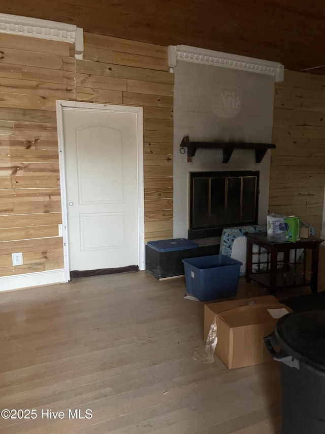 unfurnished room with wood finished floors, a glass covered fireplace, and wooden walls