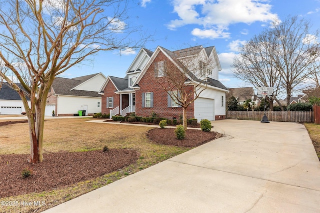 traditional home with fence, driveway, an attached garage, a front lawn, and brick siding