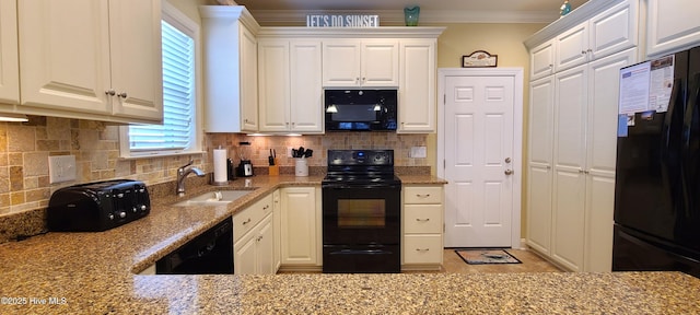 kitchen with light stone counters, a sink, white cabinets, ornamental molding, and black appliances