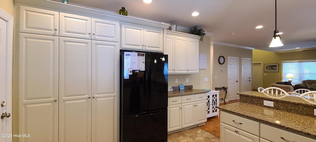 kitchen with white cabinetry, hanging light fixtures, freestanding refrigerator, dark stone counters, and crown molding