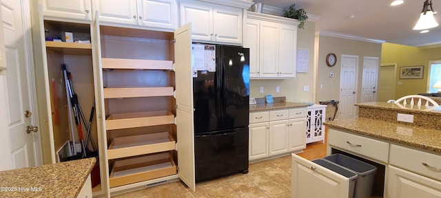 kitchen with hanging light fixtures, light stone countertops, freestanding refrigerator, and white cabinetry