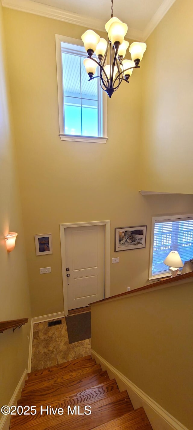 staircase featuring crown molding, visible vents, wood finished floors, a chandelier, and baseboards