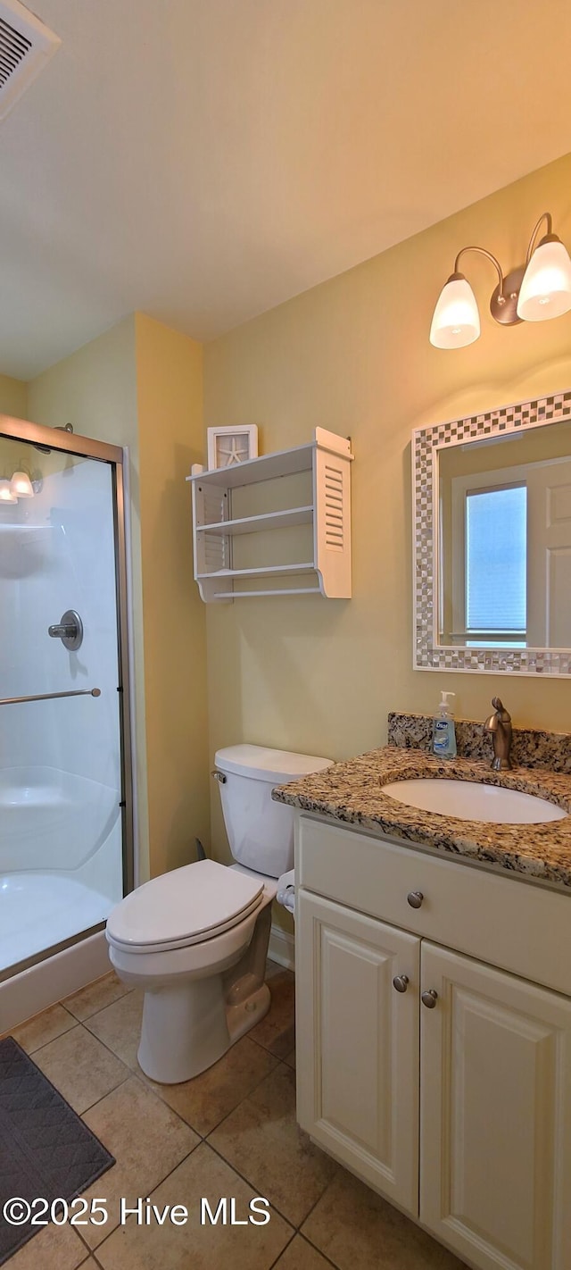 bathroom with toilet, a shower stall, vanity, and tile patterned floors