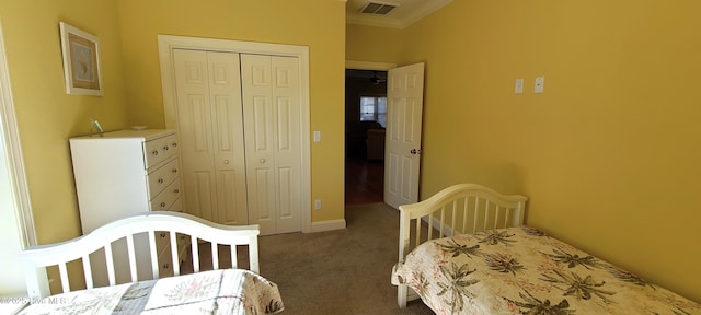 bedroom with baseboards, visible vents, ornamental molding, dark carpet, and a closet