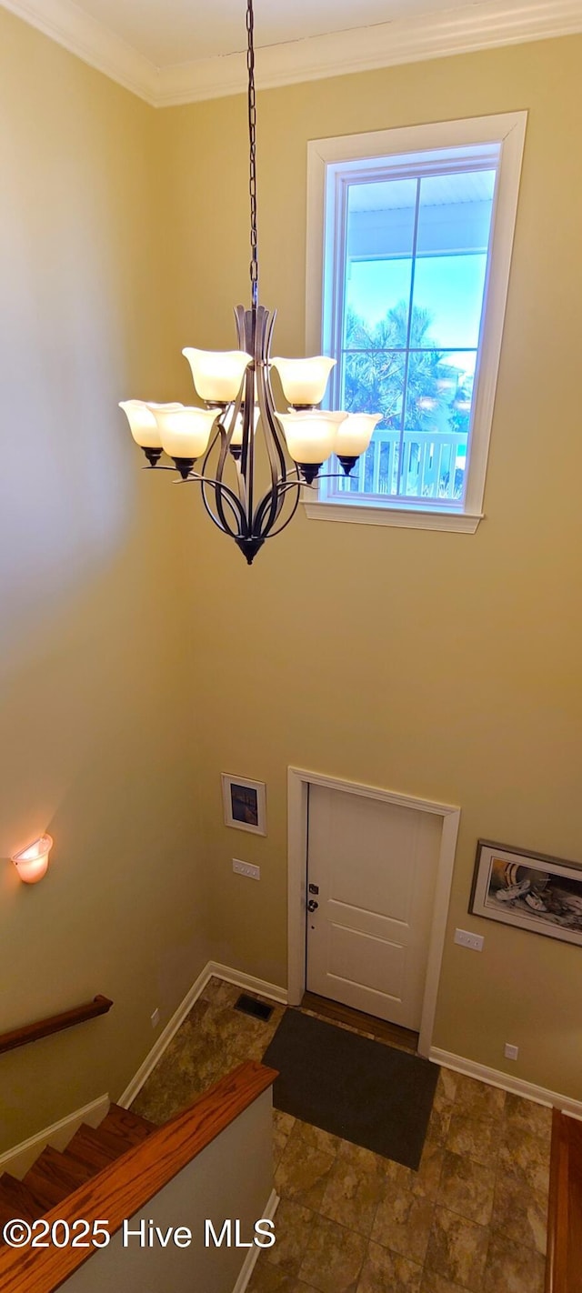 interior space featuring ornamental molding, a chandelier, and baseboards