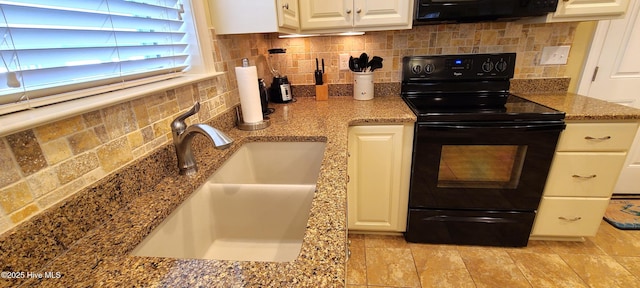 kitchen with black electric range, stone countertops, a sink, and white cabinetry