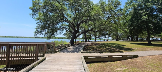 surrounding community with a water view and a lawn