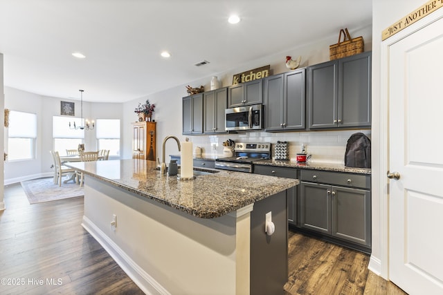 kitchen with dark wood finished floors, appliances with stainless steel finishes, decorative backsplash, and a sink