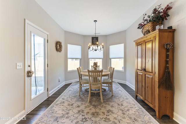 dining space with an inviting chandelier, dark wood finished floors, and baseboards