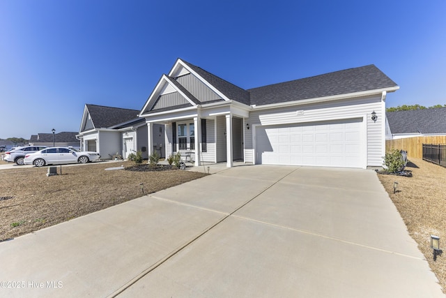 view of front facade with a shingled roof, concrete driveway, an attached garage, board and batten siding, and fence