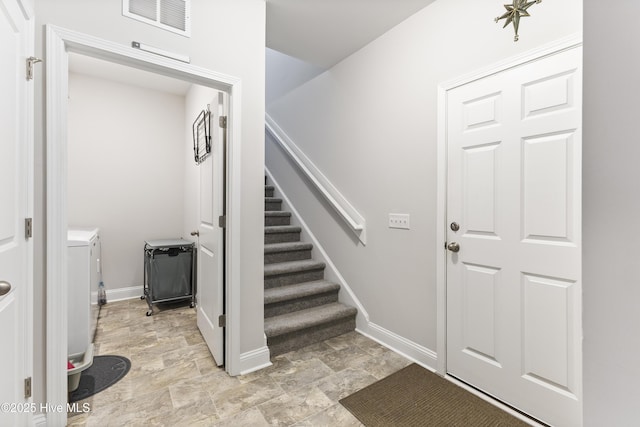 foyer with stone finish floor, visible vents, baseboards, and stairs