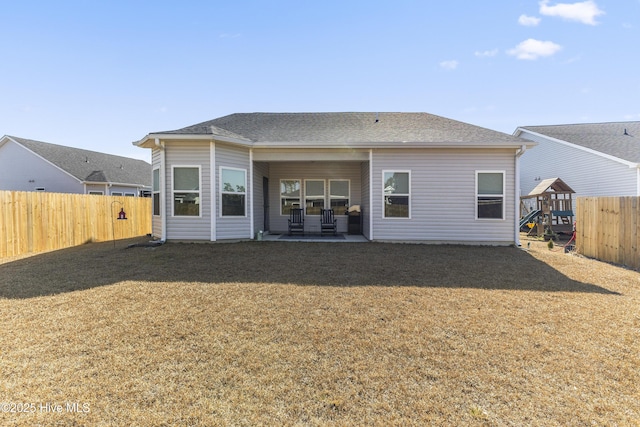 back of property featuring a fenced backyard, a shingled roof, a lawn, and a patio