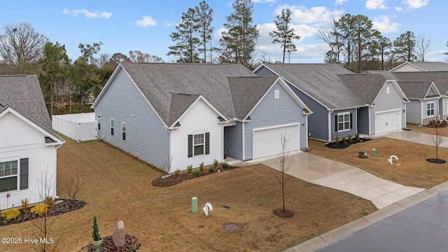 view of front of house with concrete driveway, roof with shingles, and a front yard