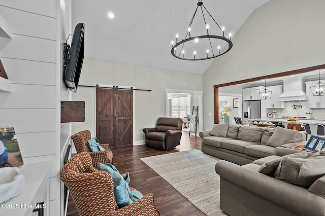 living room featuring a barn door, baseboards, dark wood-type flooring, high vaulted ceiling, and a notable chandelier