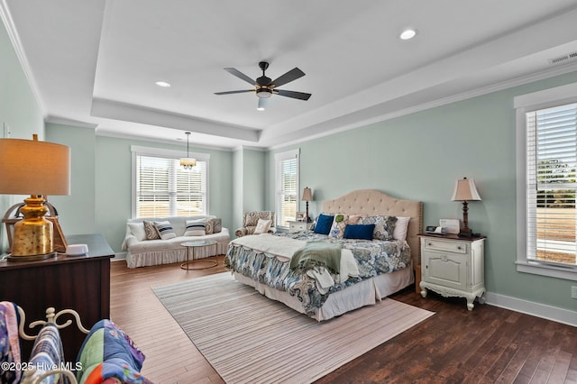 bedroom featuring visible vents, baseboards, dark wood-style floors, a tray ceiling, and crown molding