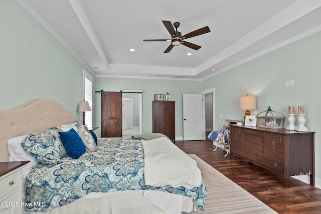 bedroom with a barn door, recessed lighting, dark wood finished floors, ornamental molding, and a raised ceiling