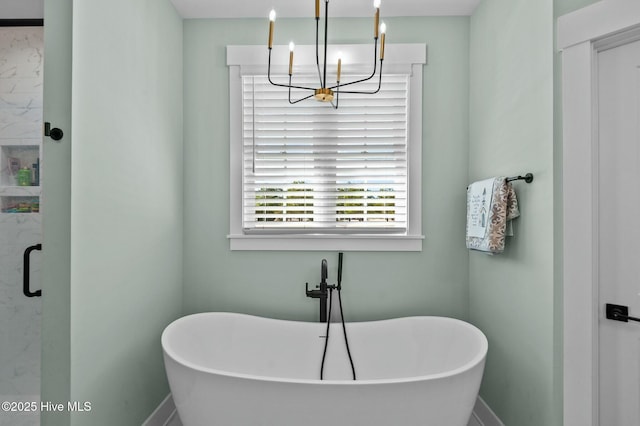 full bathroom featuring a shower stall, baseboards, a chandelier, and a freestanding bath