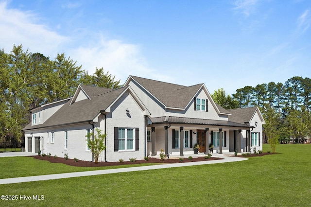 modern farmhouse with metal roof, a porch, brick siding, concrete driveway, and a front lawn