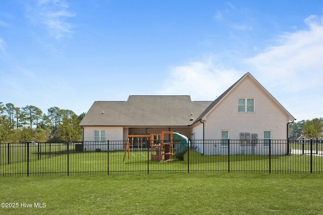 rear view of house featuring a fenced backyard, a lawn, a playground, and stucco siding