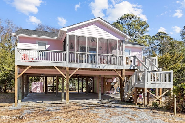 beach home featuring a carport, a sunroom, driveway, and stairs