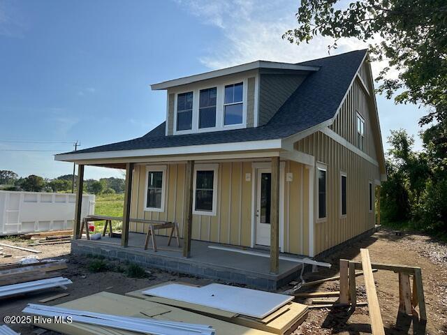 view of front facade with a porch, a shingled roof, and board and batten siding