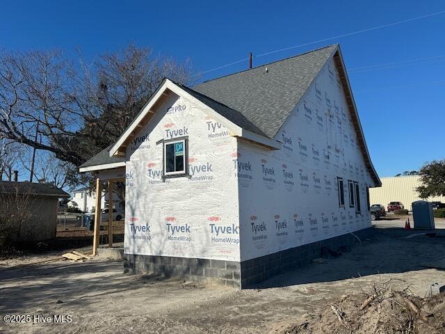 view of side of home with a shingled roof