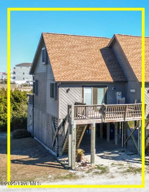 rear view of house featuring a deck, a carport, a shingled roof, and stairway